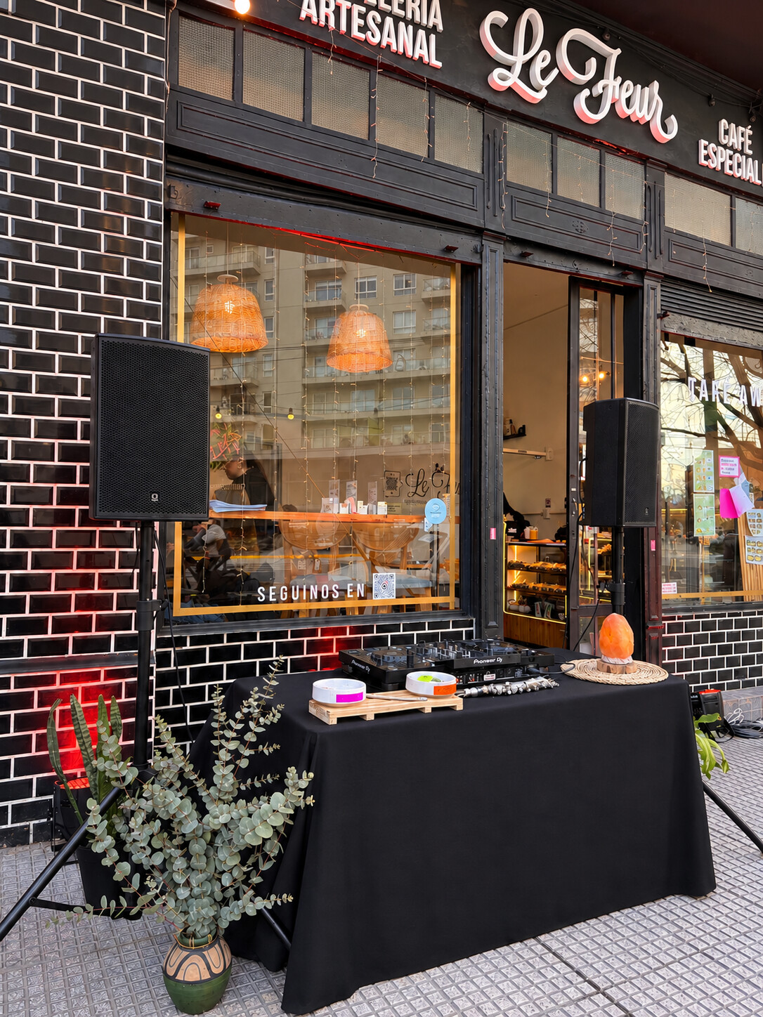 Puesta de DJ en la vereda de Le Fleur, la panadería Lefeur Bakery, con parlantes, plantas y la fachada del local de fondo