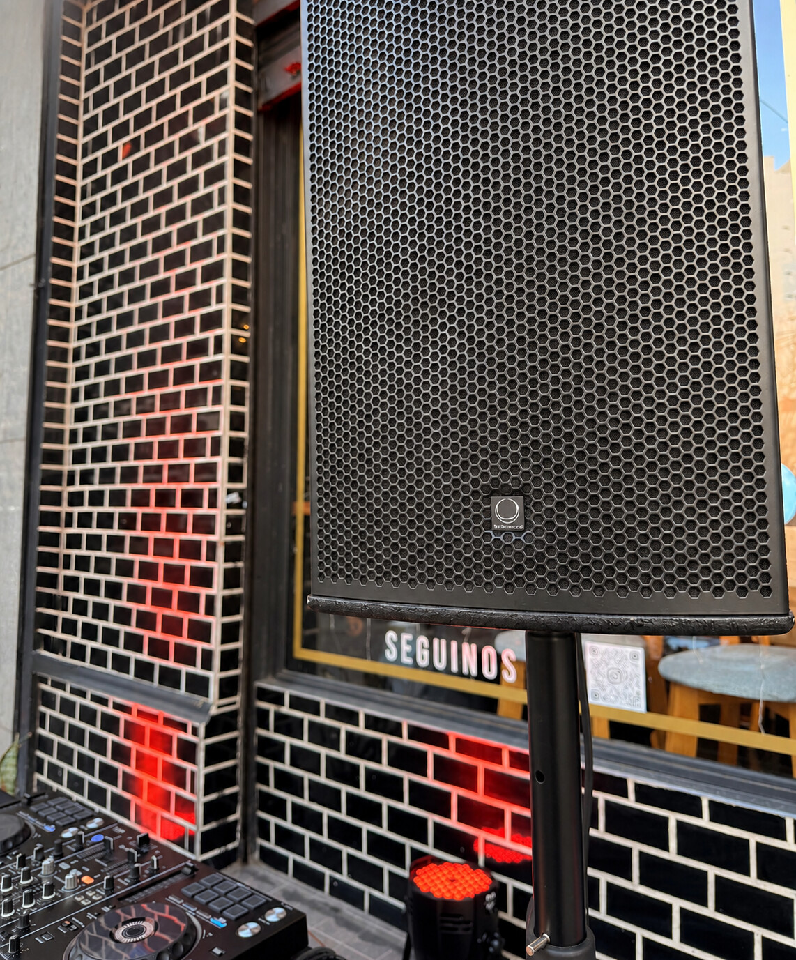 Parlante Turbosound y controladora DJ montados en la fachada de un evento de 9NCE